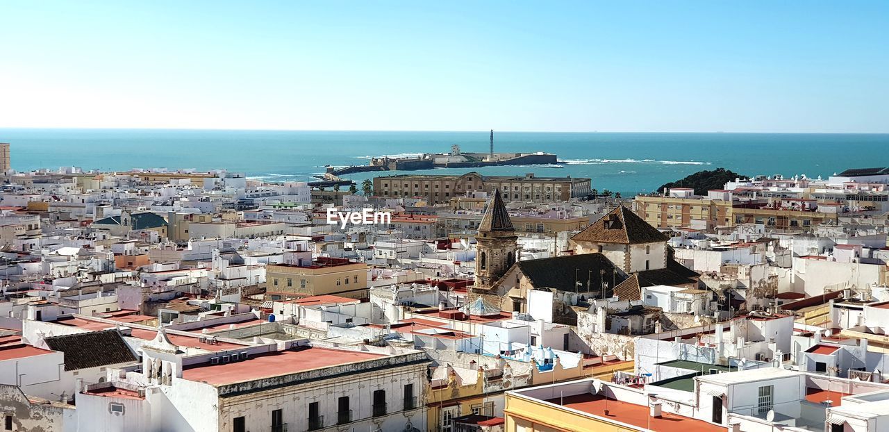 High angle view of townscape by sea against clear sky