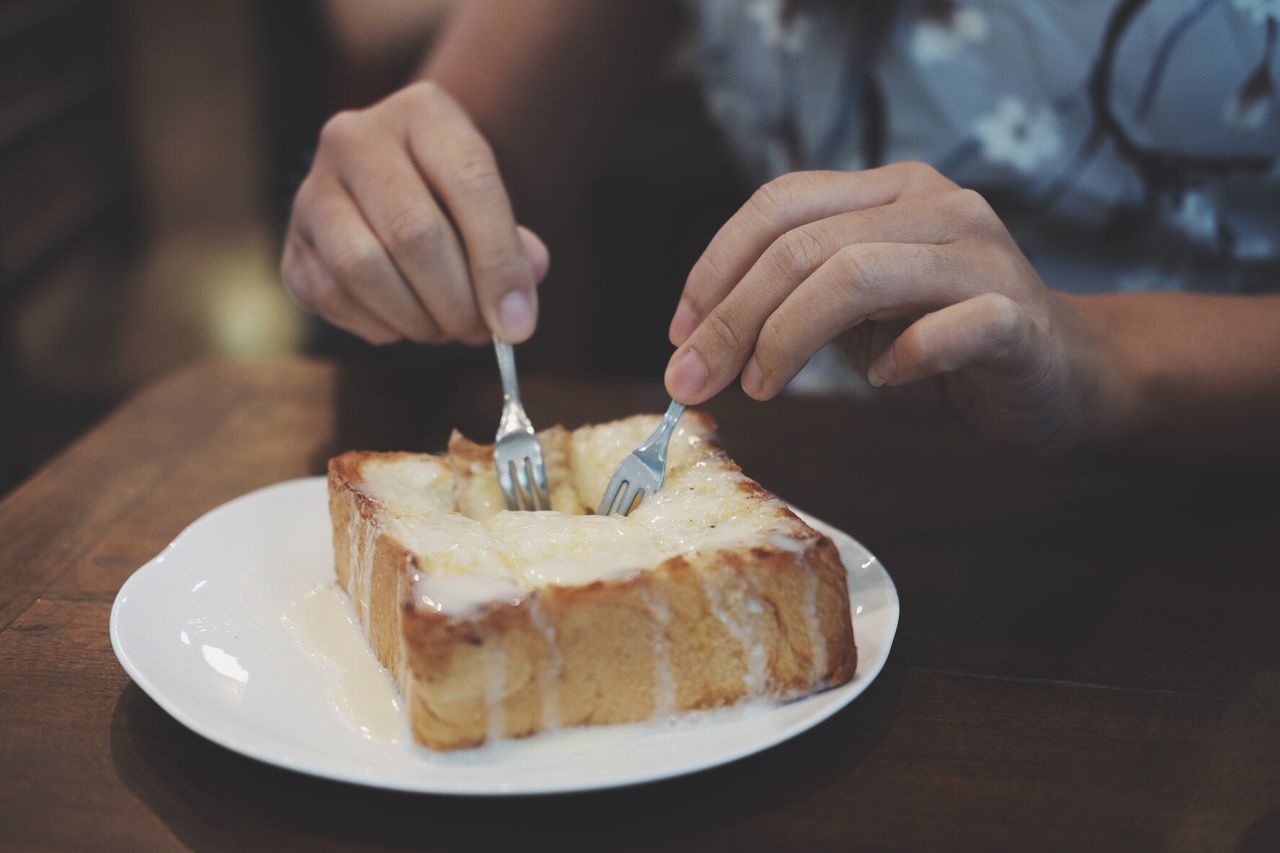 Midsection of person eating food at table