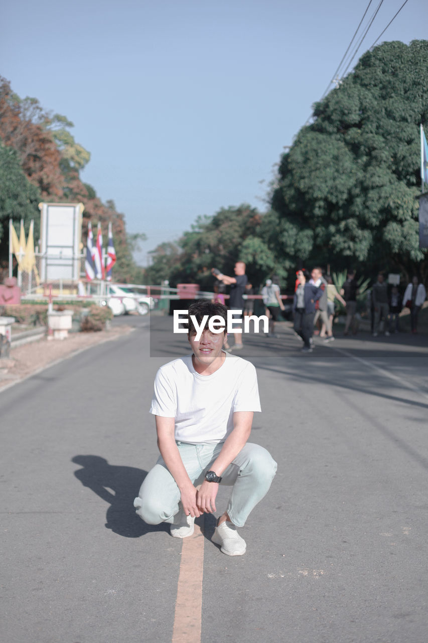 PORTRAIT OF SMILING MAN SITTING ON ROAD