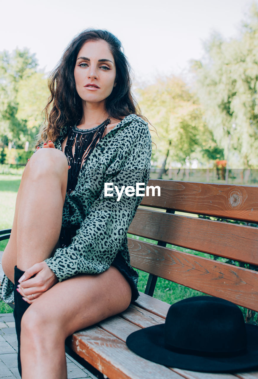 Portrait of beautiful stylish woman sitting on the bench outdoor. millennials generation.