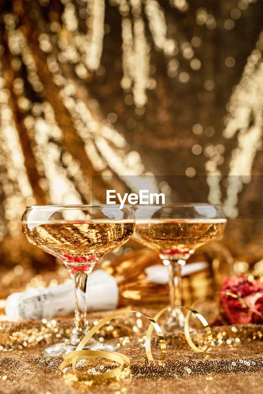 New years eve gold party table with two champagne glasses with bottle and pomegranate
