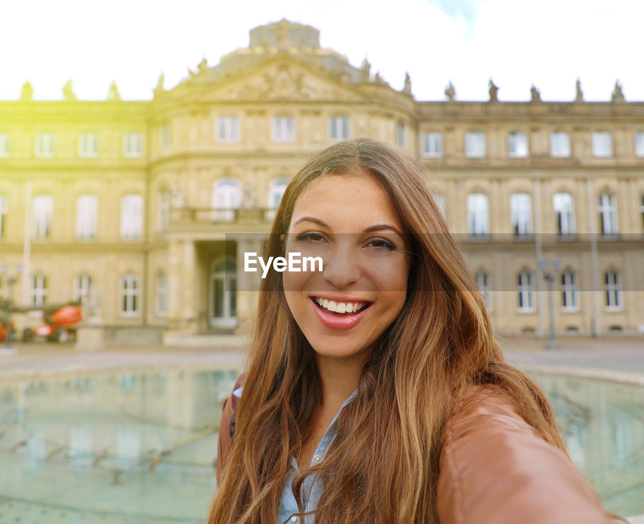 Smiling cheerful young woman in front of neues schloss  of stuttgart, germany.