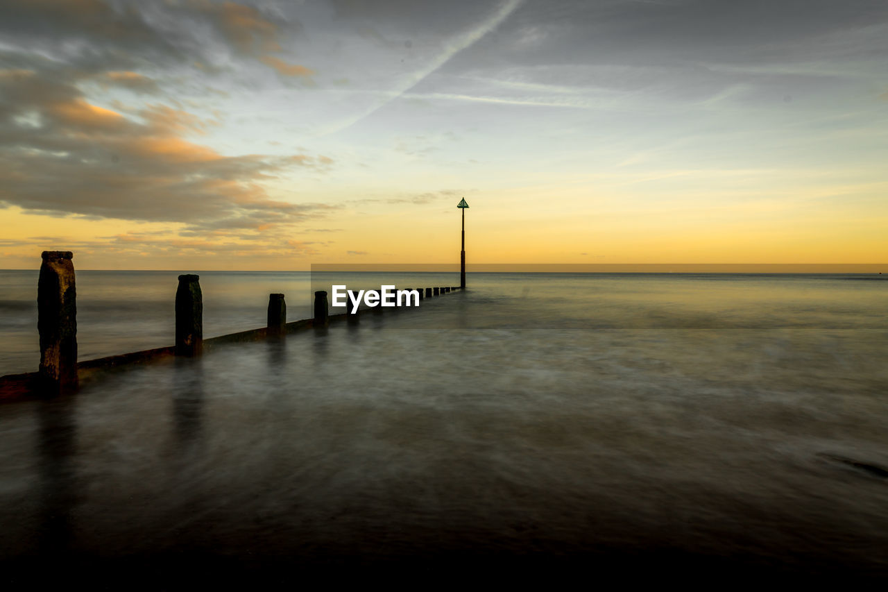 Pier on sea against sky during sunset