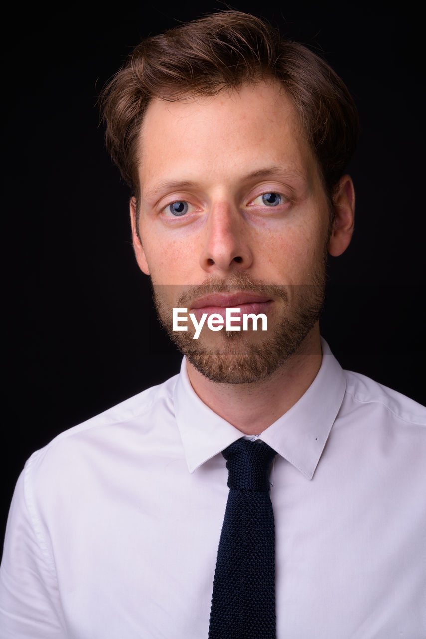 Portrait of young man against black background