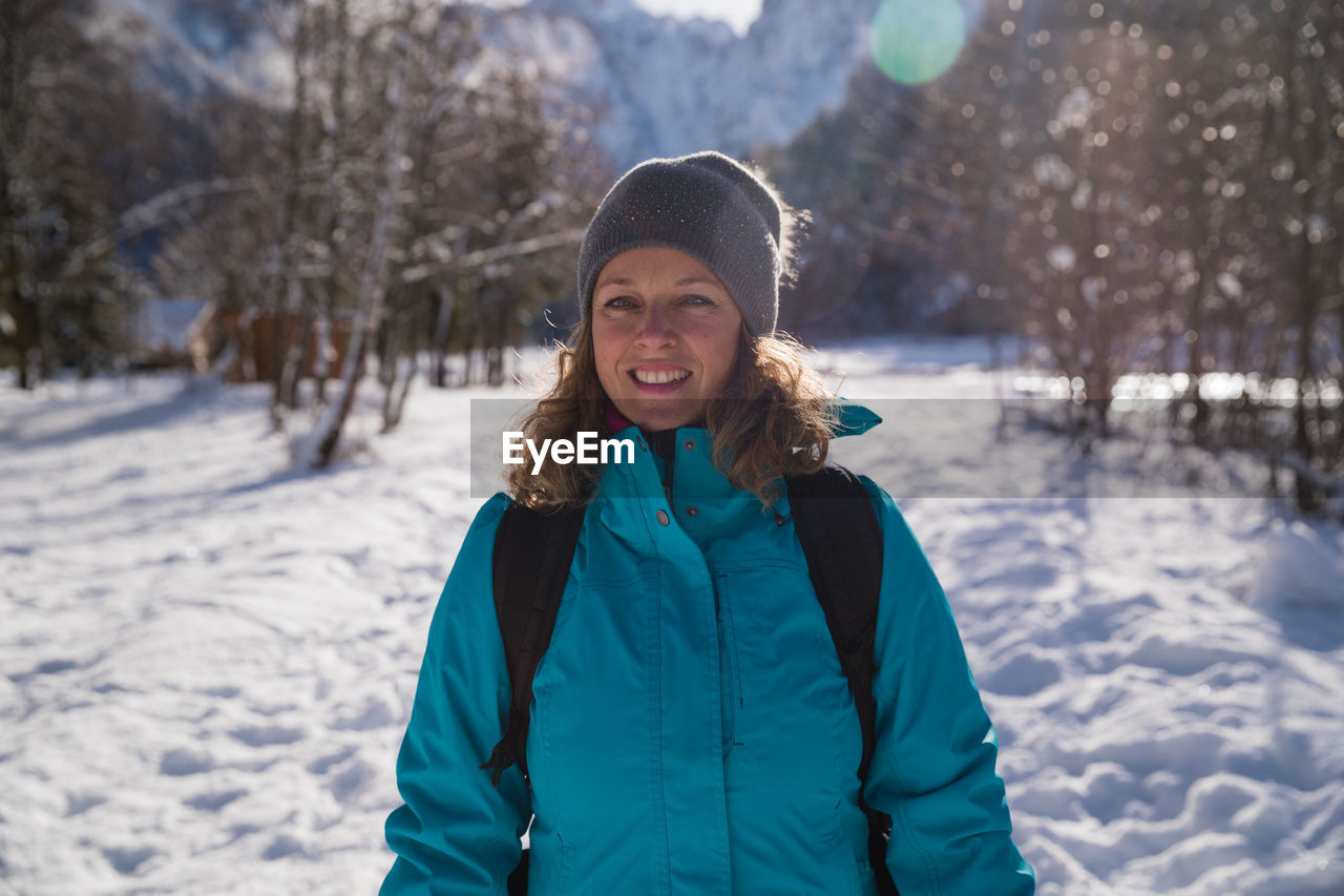 Portrait of smiling woman standing on snow covered land
