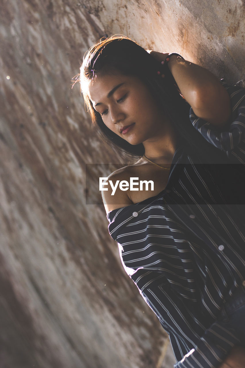 Young woman standing by wall