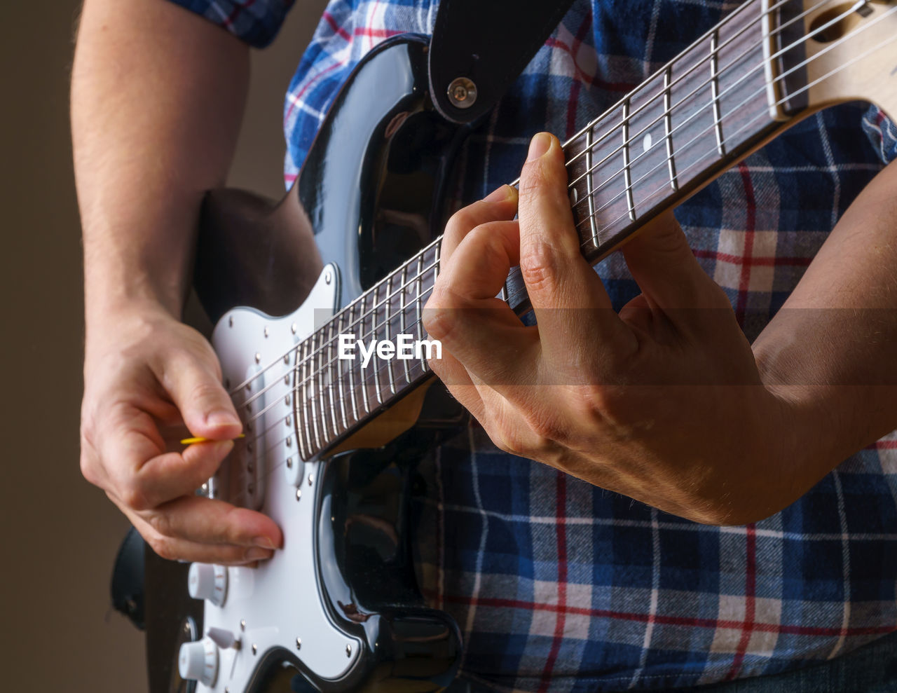 MIDSECTION OF MAN PLAYING GUITAR IN OFFICE