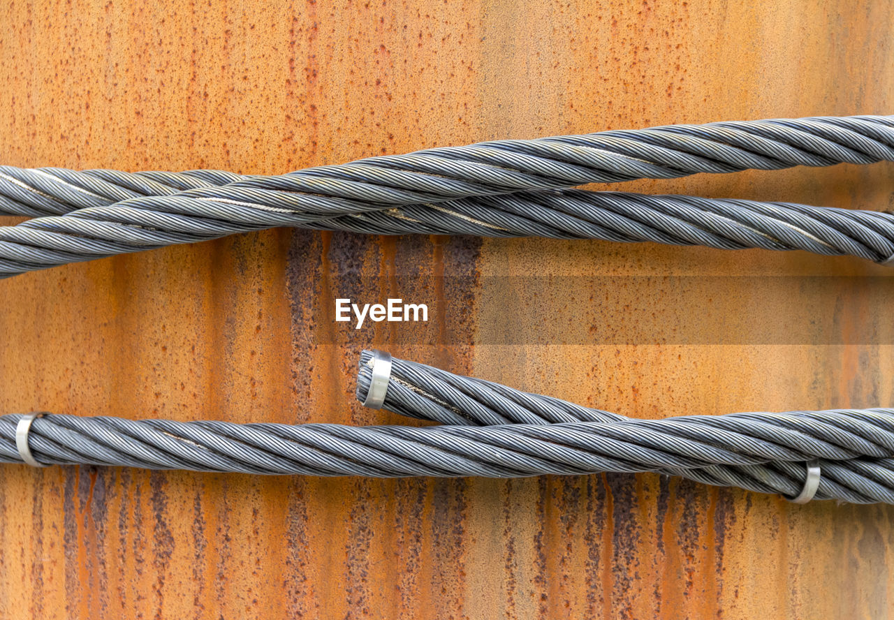 CLOSE-UP OF ROPES TIED ON METAL WALL