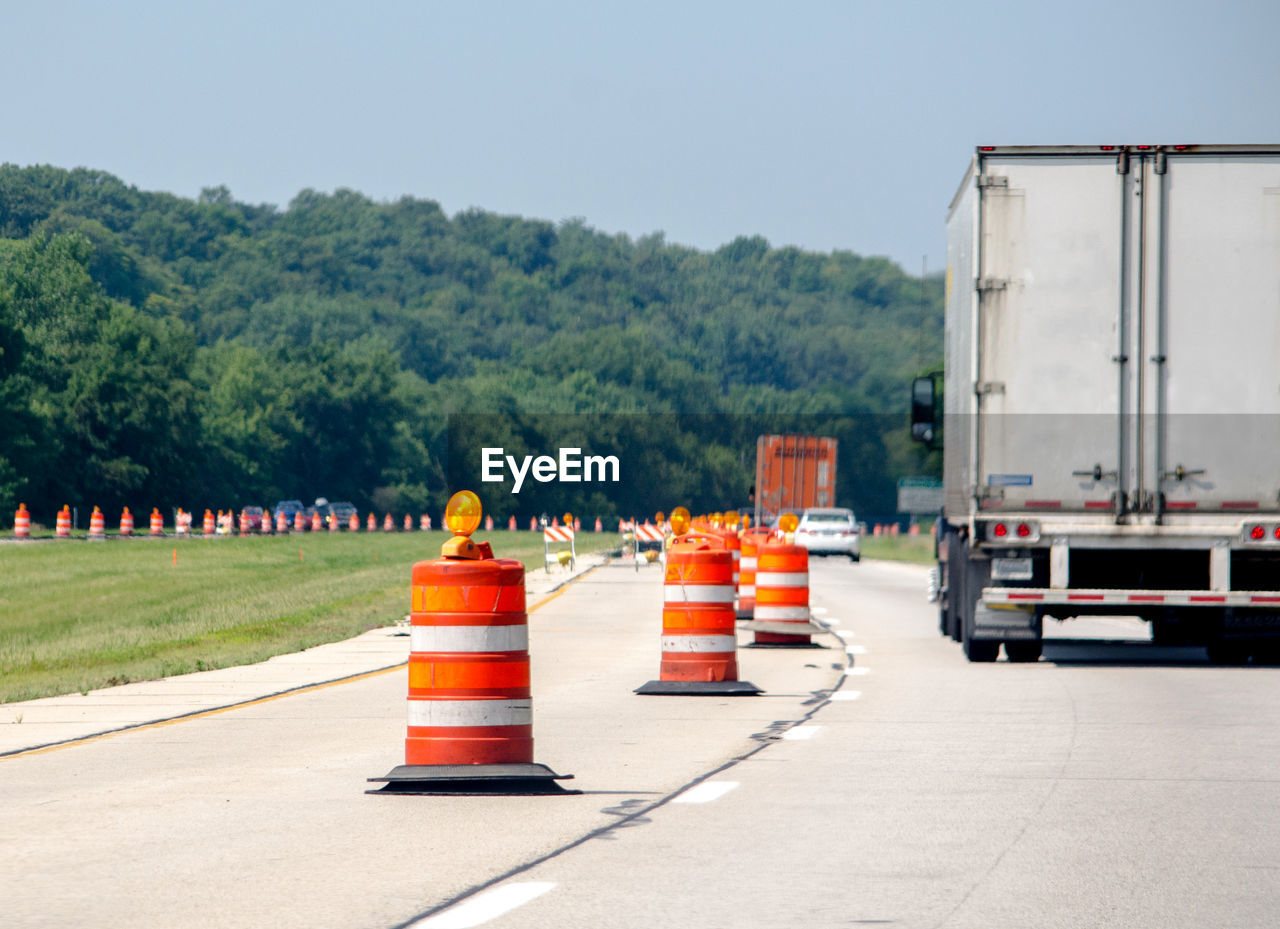 Vehicles travel the usa highways as orange construction cones pop up all over, as road repairs begin