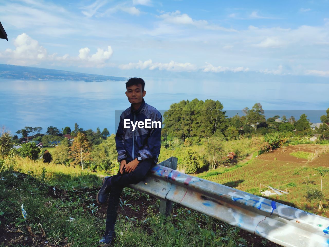 Young man looking at waterfall against sky