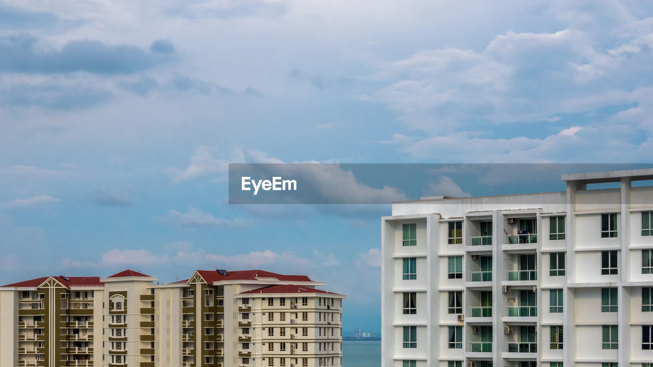 Low angle view of buildings against cloudy sky