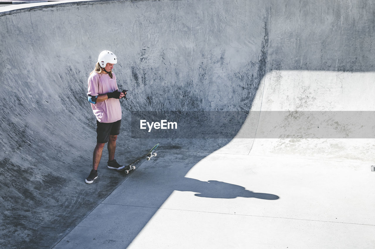 Sportsman using mobile phone at skateboard park