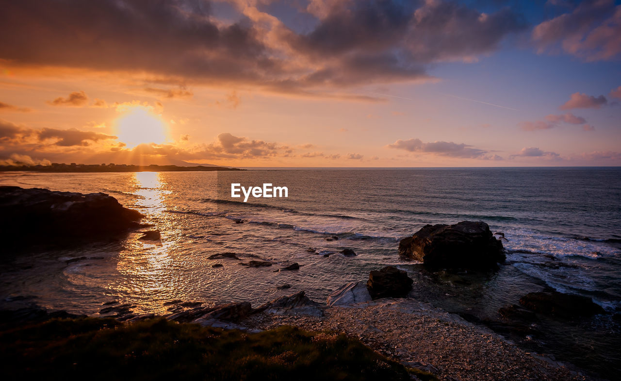 Scenic view of sea against dramatic sky during sunset