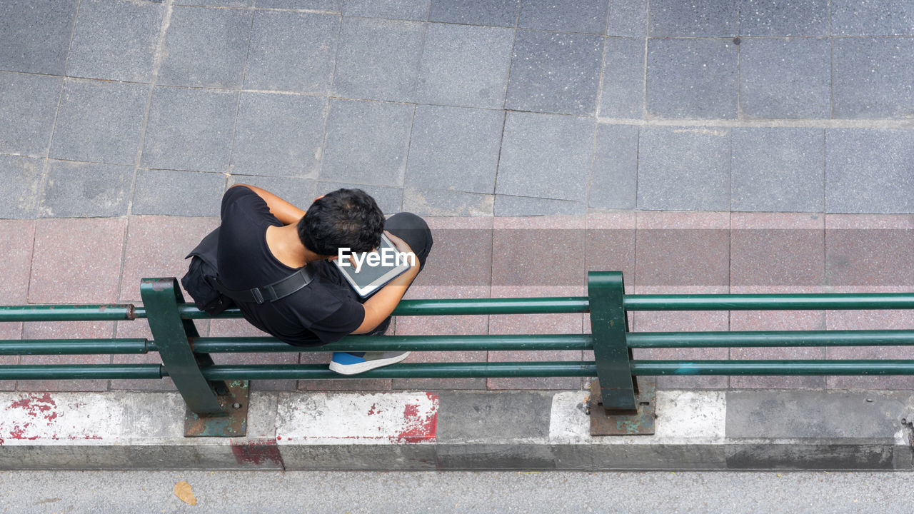 FULL LENGTH OF MAN SITTING ON RAILING