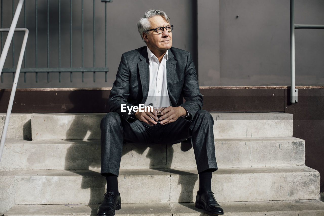 Senior businessman sitting on concrete stairs