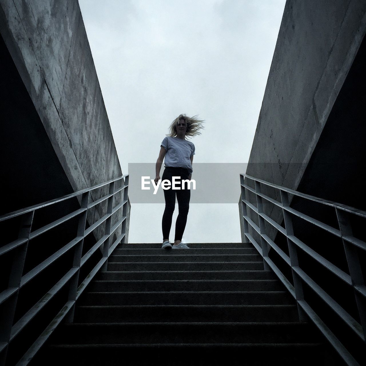 Low angle view of woman on staircase against sky