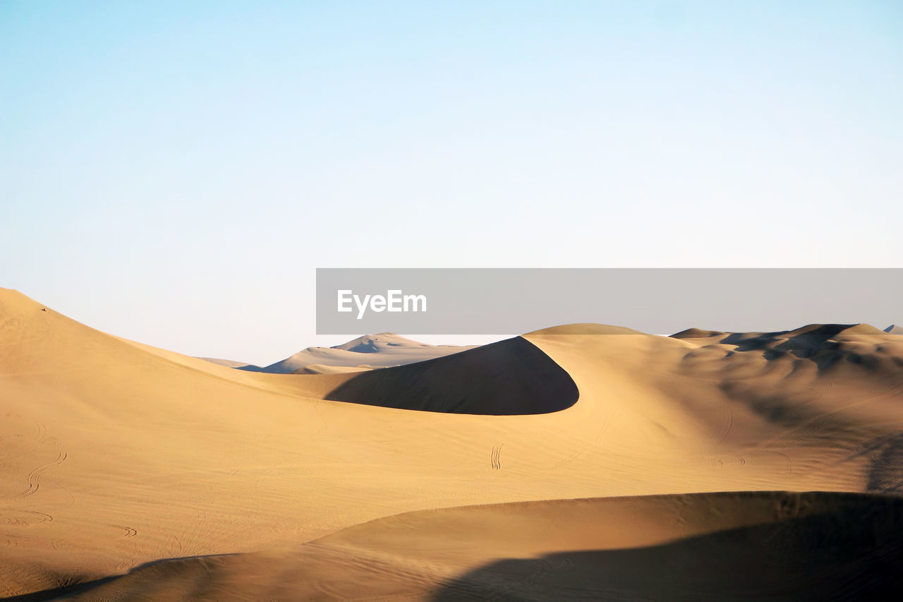 Sand dunes in desert against clear sky