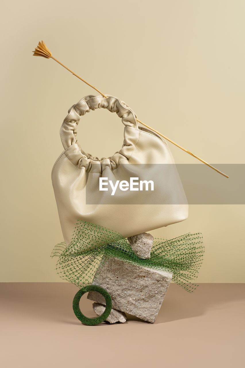 Conceptual creative modern still life, balance composition.beige handbag  a minimalistic background