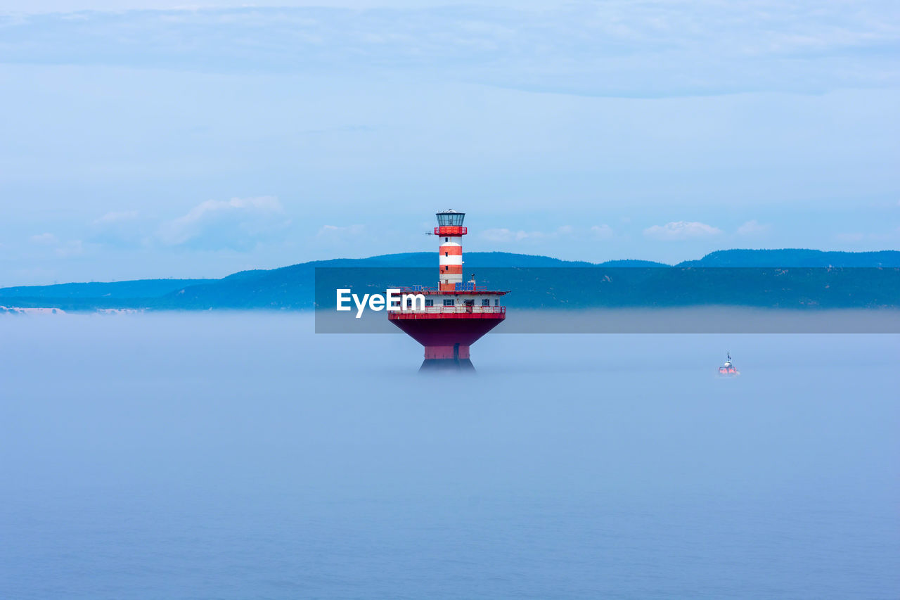 Lighthouse in sea against blue sky