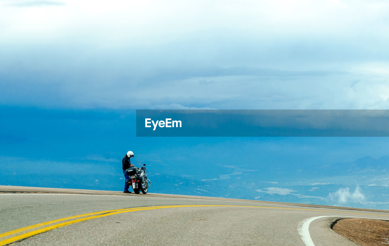 Person standing with motorcycle at roadside