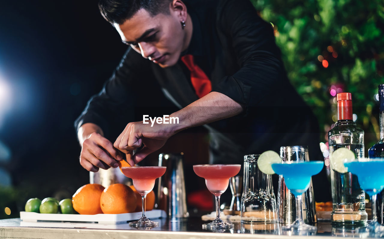 Young bartender working in party at night