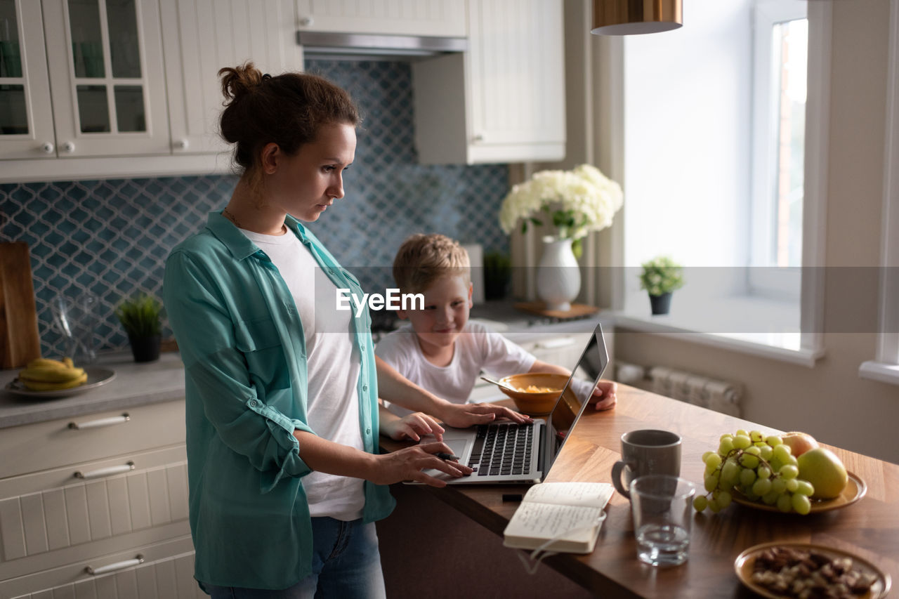 Mother working near eating son