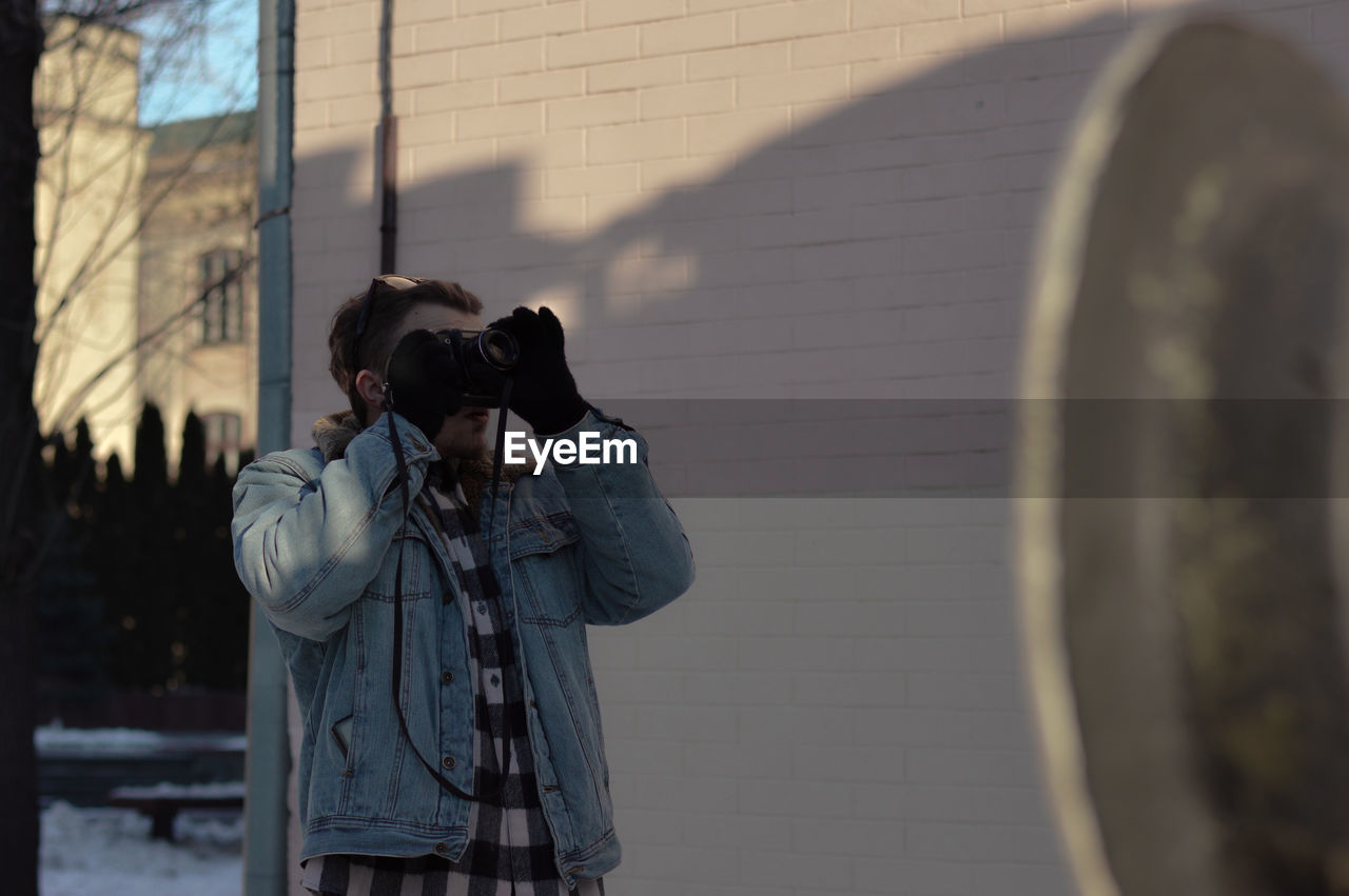 Man photographing through camera against building