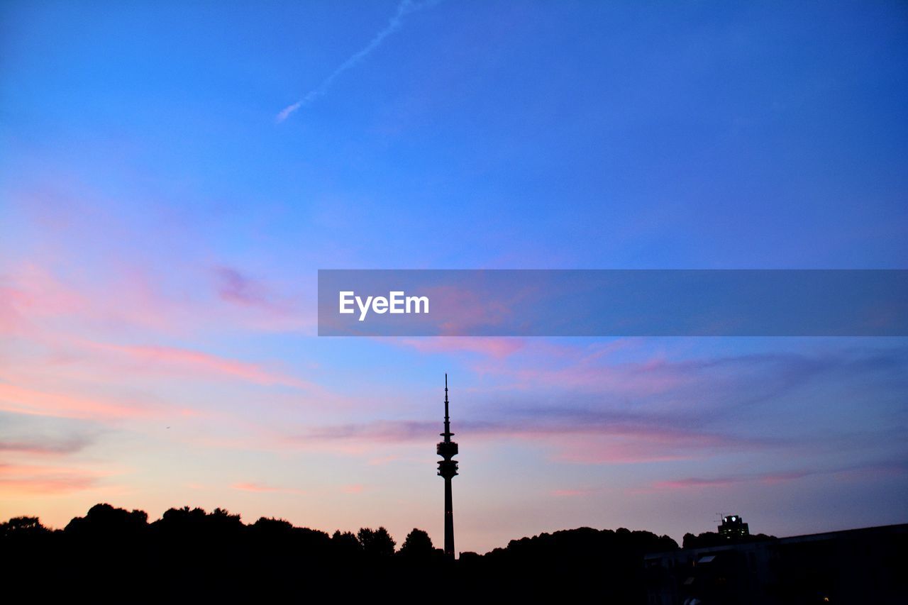 SILHOUETTE OF COMMUNICATIONS TOWER AND BUILDINGS AGAINST SKY