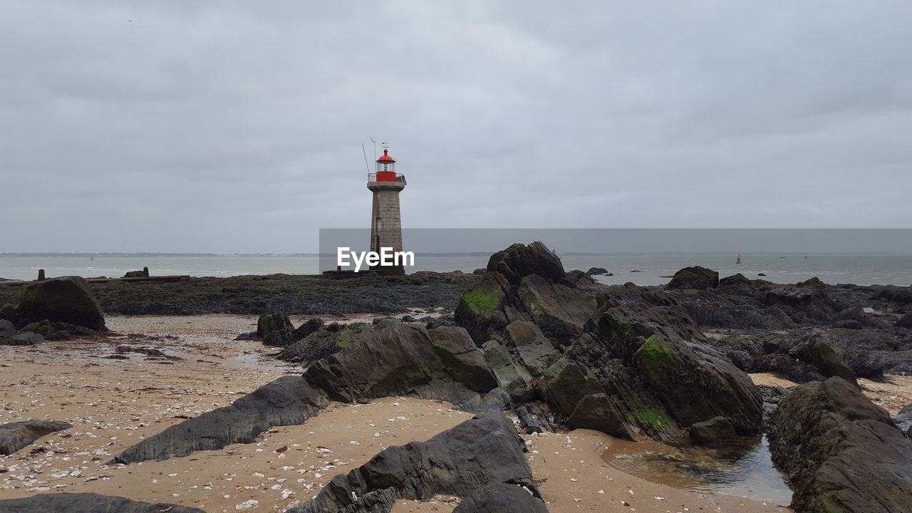 Lighthouse by sea against sky