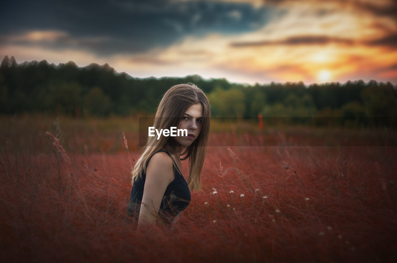 Portrait of woman on field against sky during sunset