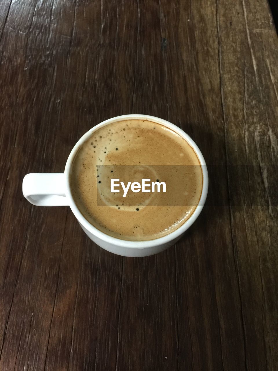 HIGH ANGLE VIEW OF COFFEE CUP ON WOODEN TABLE