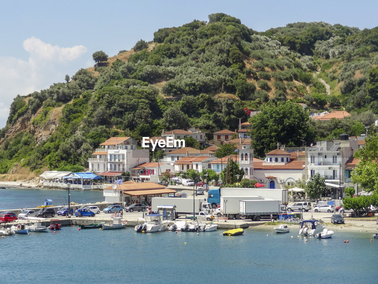 SAILBOATS MOORED IN SEA BY BUILDINGS AGAINST SKY