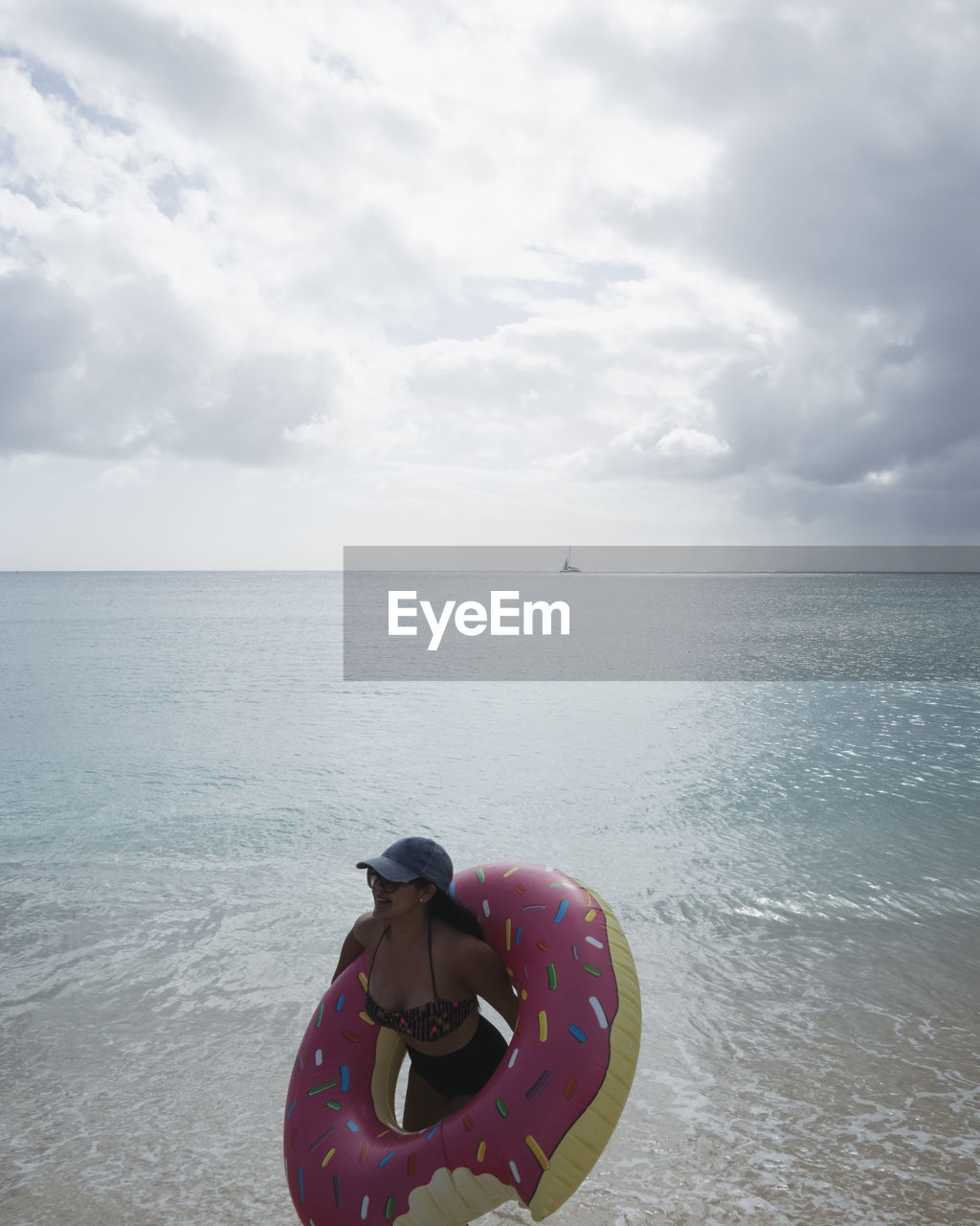 Woman with inflatable ring by sea against sky