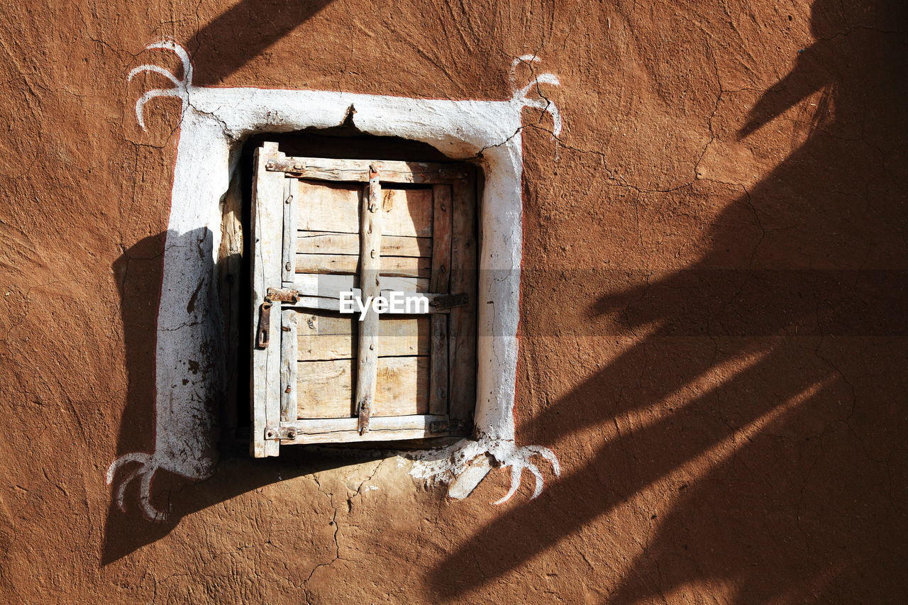 Closed wooden window of old mud hut