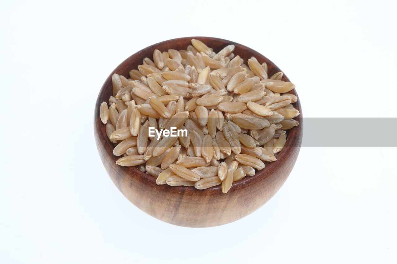 Close-up of wheat in bowl against white background