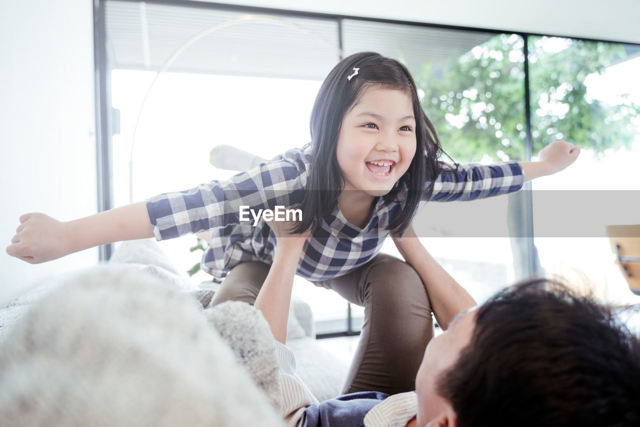 Man lifting daughter at home