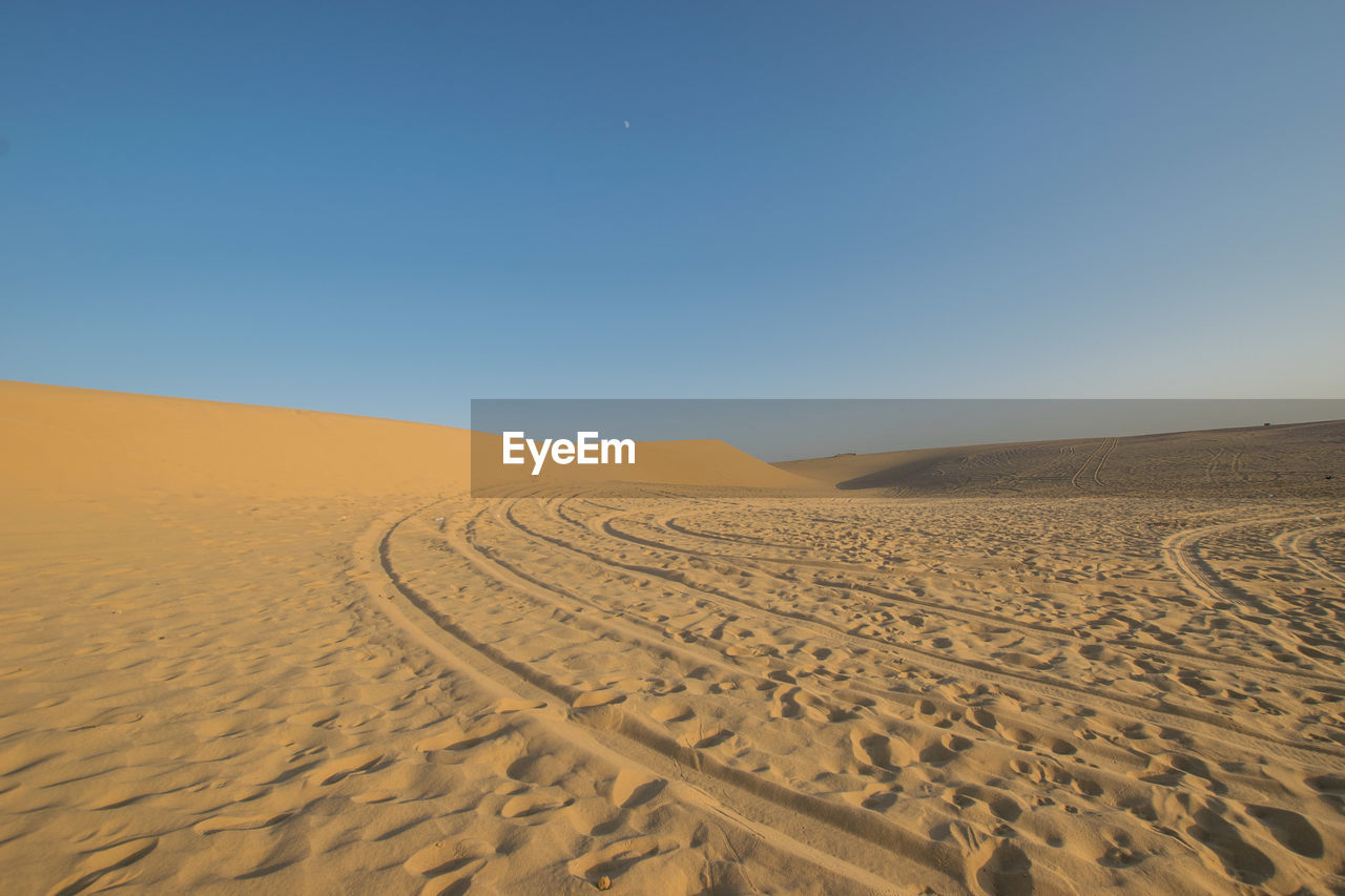 Scenic view of desert against clear blue sky