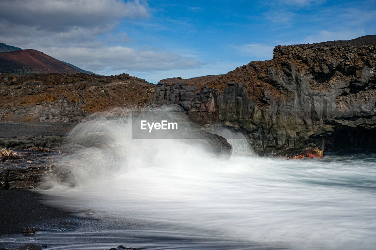 Scenic view of waterfall against sky