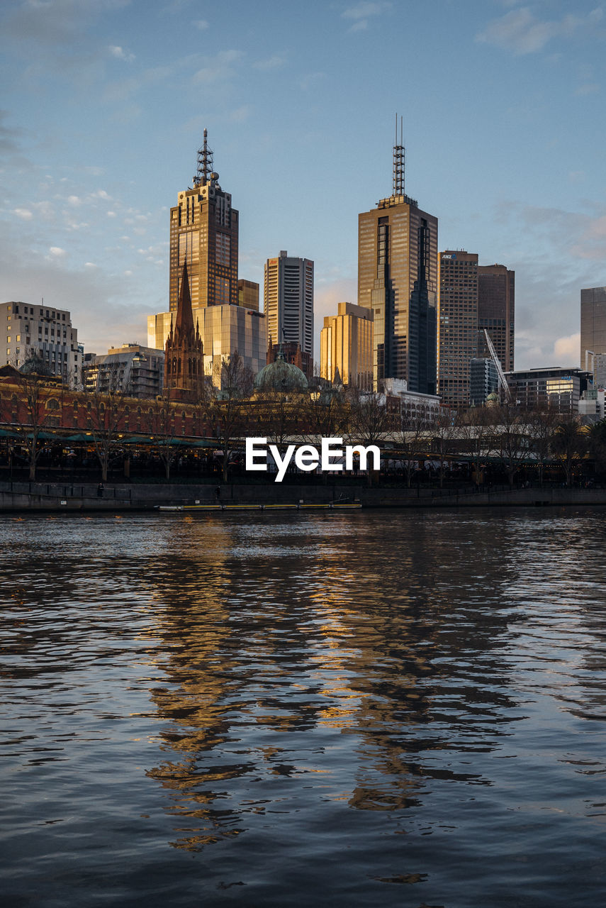 River in front of cityscape against sky in city