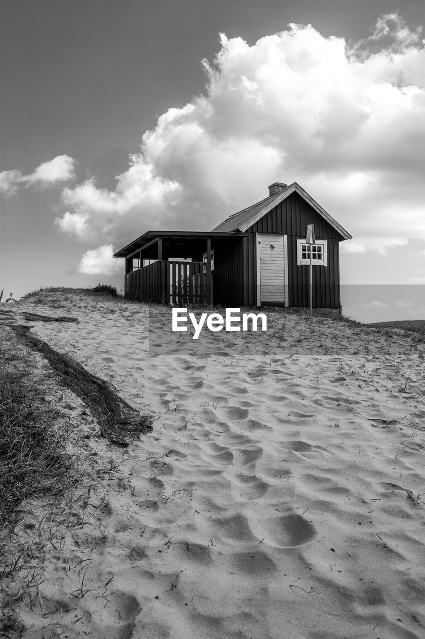 Black and white edit of an fishing hut on the beach. a fishing net can be seen. 