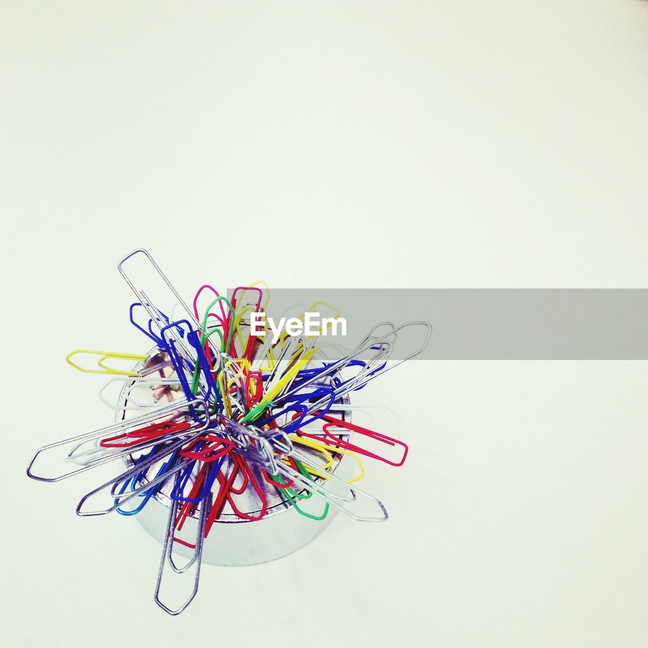 High angle view of paper pins on magnet against white background