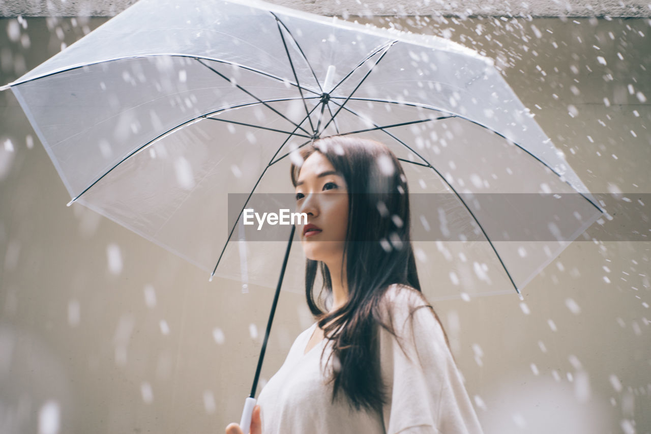 Young woman with umbrella looking away