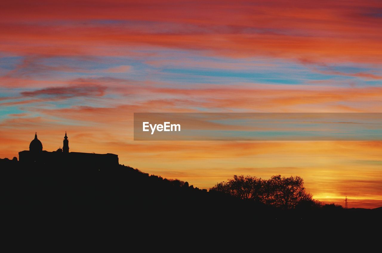 Silhouette of trees against cloudy sky during sunset