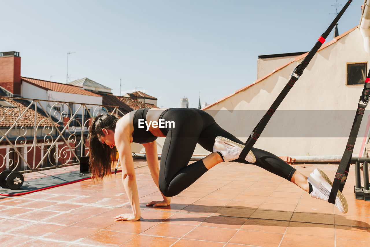 Woman doing urban workout for arms and chest with trx fitness straps. healthy outdoor training