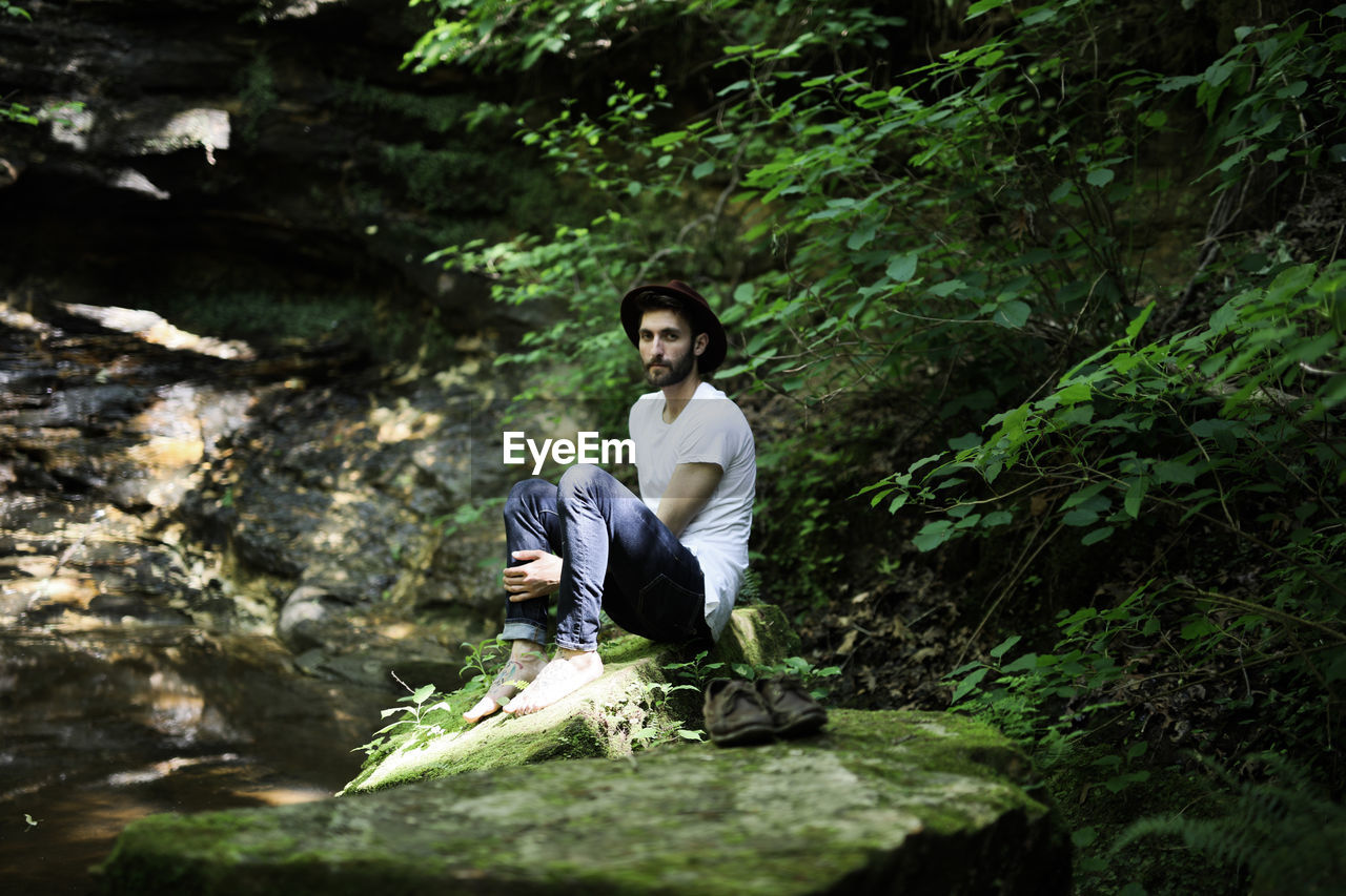 Young man sitting on rock in forest