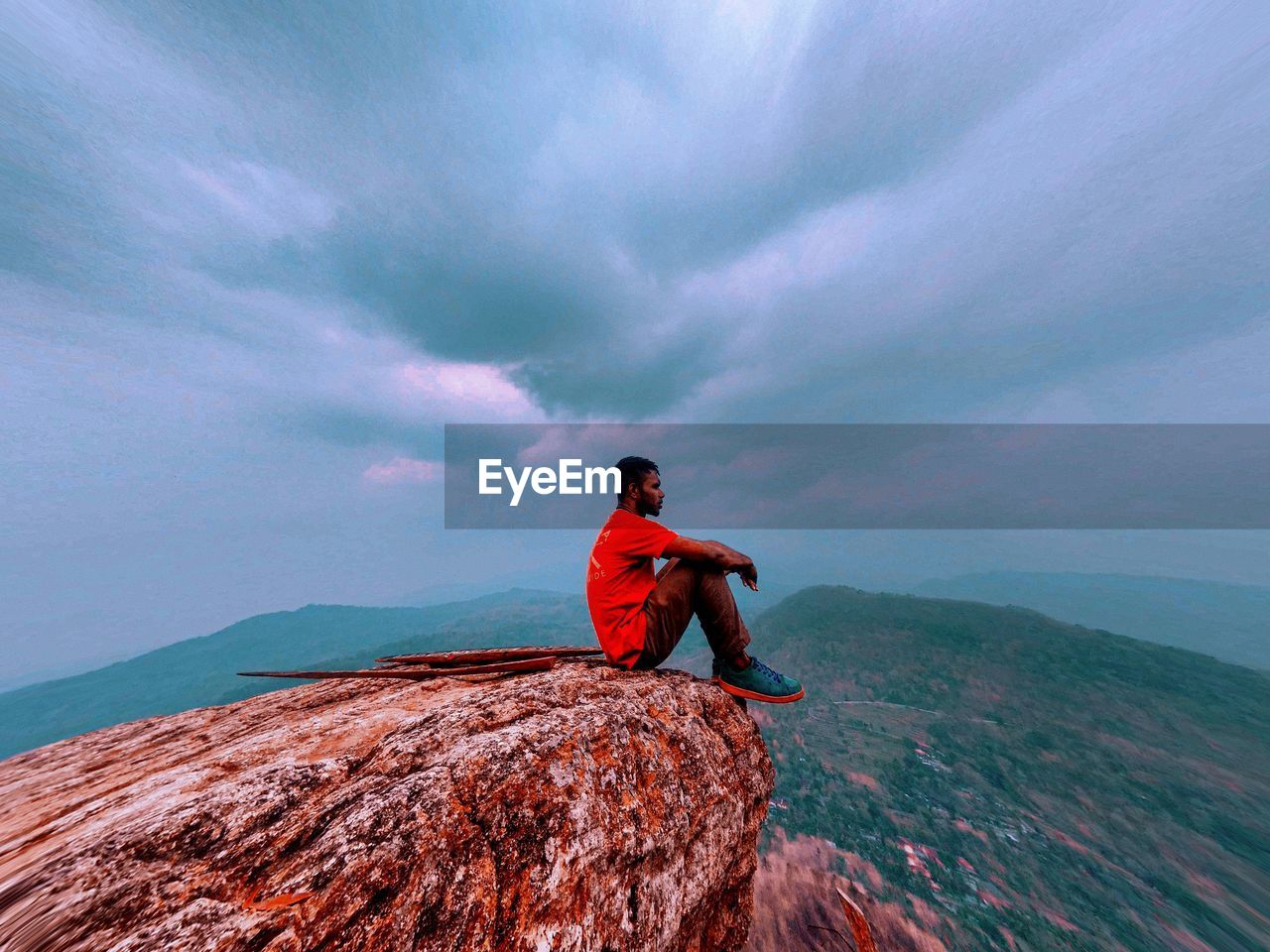 MAN ON ROCK IN SEA AGAINST SKY