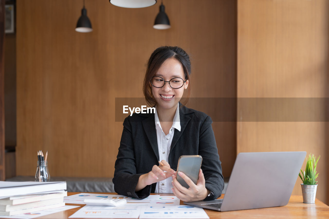 portrait of young woman using laptop at desk in office