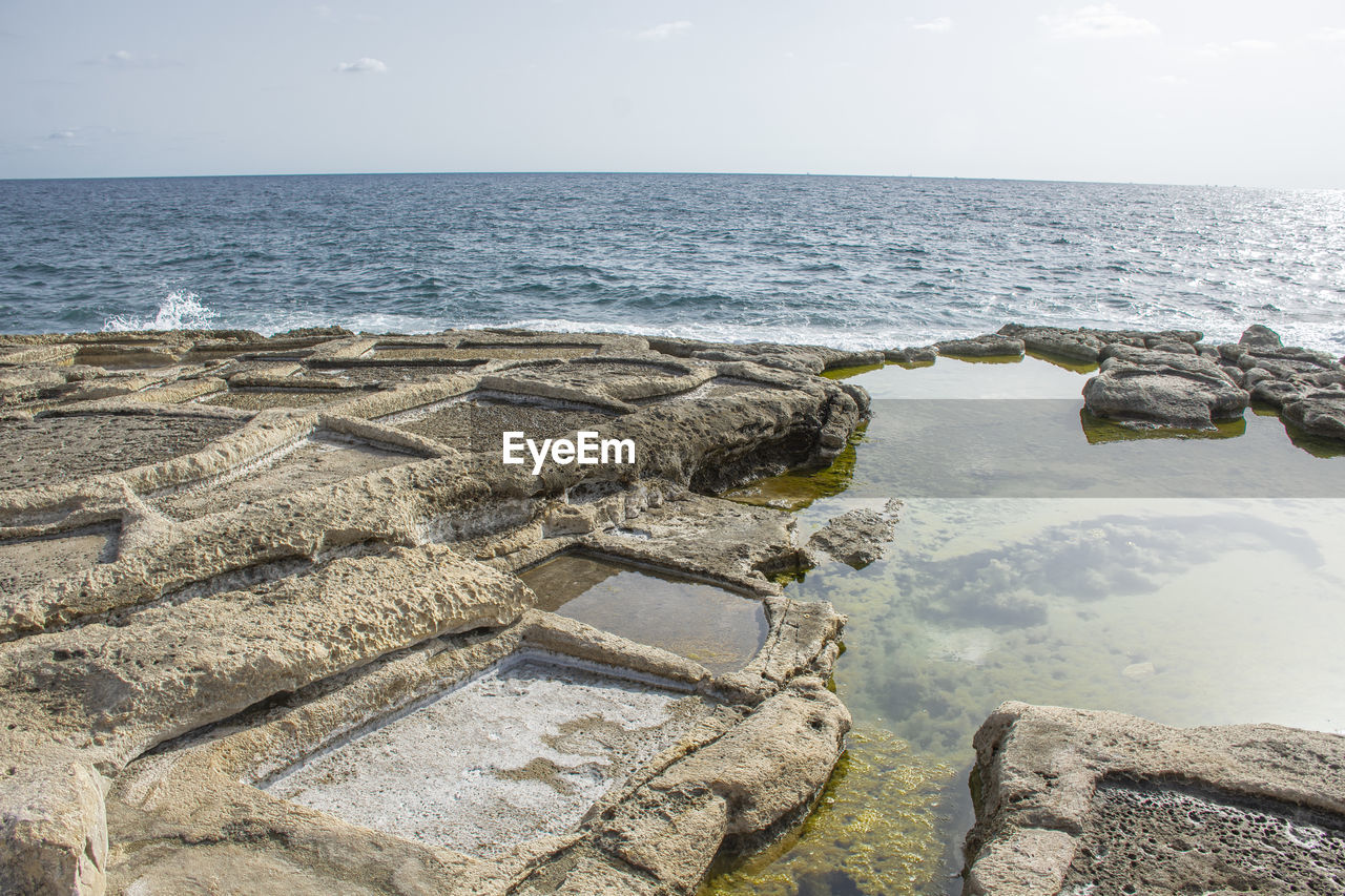 water, sea, horizon over water, shore, sky, horizon, coast, rock, nature, land, beach, scenics - nature, beauty in nature, ocean, tranquility, day, tranquil scene, no people, terrain, breakwater, outdoors, sand, travel destinations, travel, idyllic, body of water, sunlight