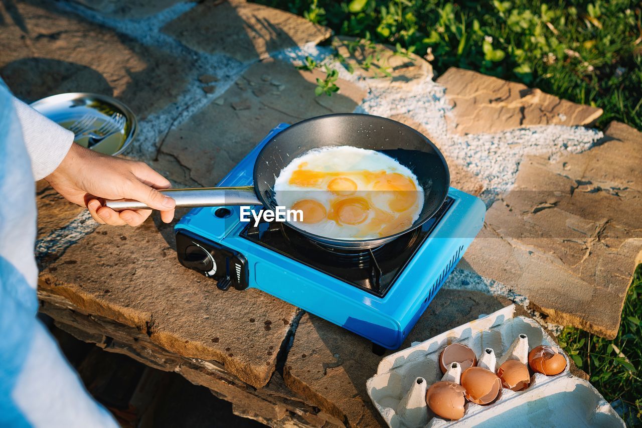 High angle view of man preparing omelet food on camping stove