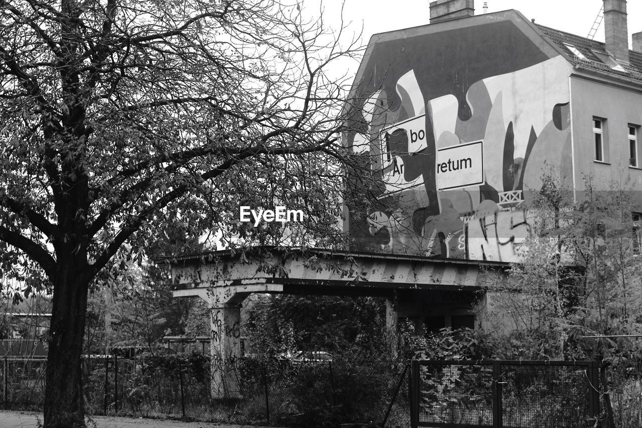 LOW ANGLE VIEW OF BUILT STRUCTURE AND BARE TREES AGAINST SKY